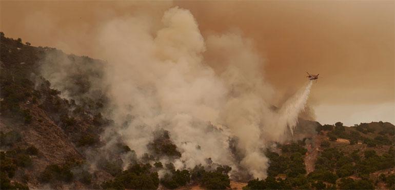 A water-dropping helicopter drops on flames from the advancing Lake Fire in Los Olivos, Calif., Saturday, July 6, 2024. (AP Photo/Eric Thayer)