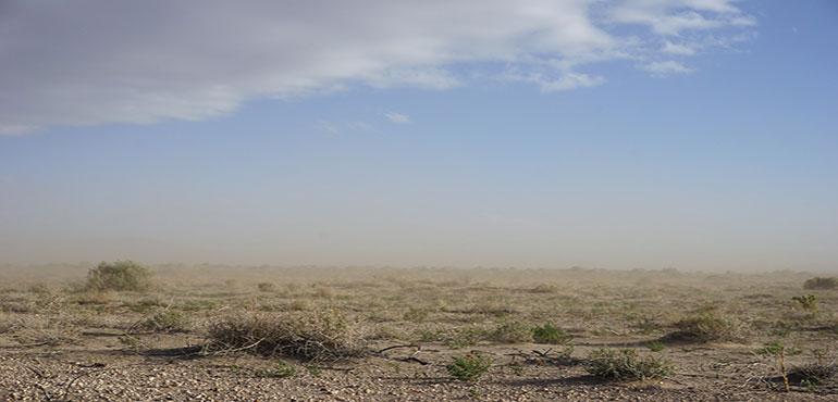 A wall of dust in the background of a desert. (Image by Mike from Pixabay)